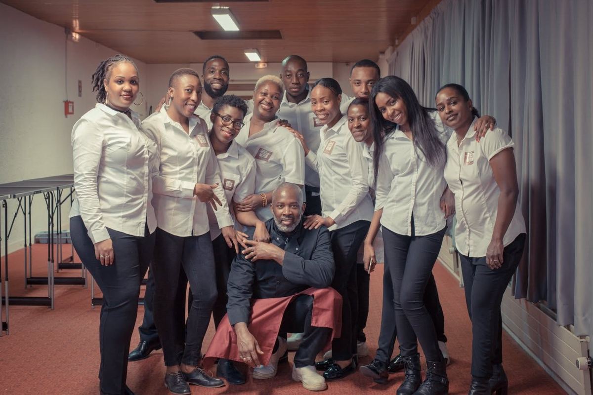 La brigade de la maison : une douzaine de personnes en chemise blanche, souriantes, réunies autour d'un cuisinier en veste noire.